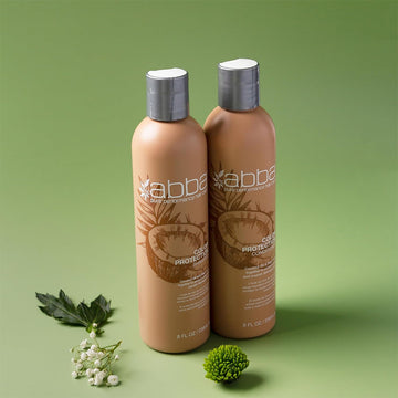 ABBA Color Protection Shampoo and Conditioner 8 oz bottles displayed with greenery on a soft green background