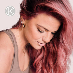 Model with long, wavy rose gold hair and dark brunette roots demonstrating the result of Keracolor Color + Clenditioner for Brunettes Rose Gold