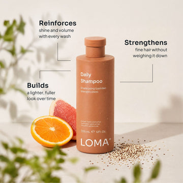 Loma Daily Shampoo 12 oz bottle with orange and grapefruit slices, highlighting shine, volume, and lightweight strengthening for fine hair