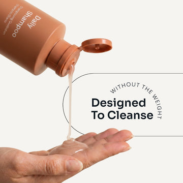 Loma Daily Shampoo dispensed from an open orange bottle onto a hand, demonstrating its lightweight texture