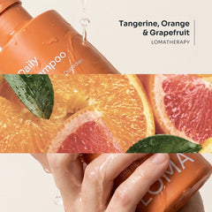 Loma Daily Shampoo held in wet hands beside tangerine, orange, and grapefruit imagery, highlighting the citrus LomaTherapy blend