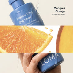 Loma Moisturizing Shampoo held in wet hands beside mango and orange imagery, highlighting the Mango and Orange LomaTherapy blend