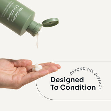 Loma Nourishing Conditioner dispensed from an open green bottle onto a hand, demonstrating its creamy texture