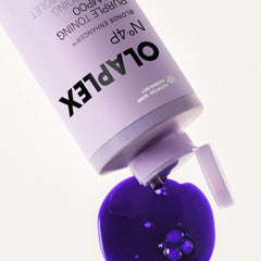 Close-up of OLAPLEX Nº.4P Blonde Enhancer Purple Toning Shampoo dispensing a rich purple formula onto a white surface