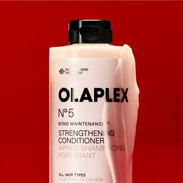 OLAPLEX Nº.5 Bond Maintenance Strengthening Conditioner bottle close-up against a red background