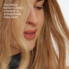 Close-up of a blonde model with long fine hair demonstrating weightless volume, hydration, and strength with OLAPLEX Nº.5FINE Volumizing Conditioner