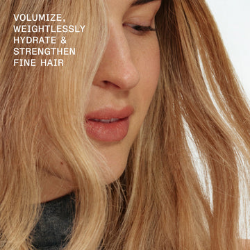 Close-up of a blonde model with long fine hair demonstrating weightless volume, hydration, and strength with OLAPLEX Nº.5FINE Volumizing Conditioner