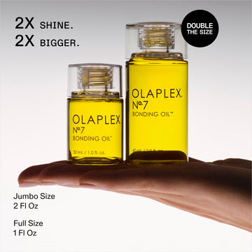 OLAPLEX Nº.7 Bonding Oil size comparison showing 1 oz full-size and 2 oz jumbo bottles on a hand
