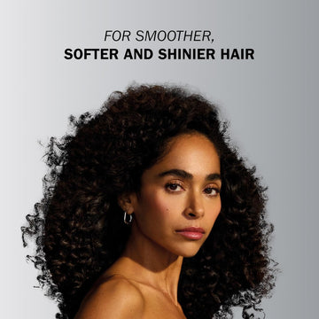 Model with voluminous defined dark curls demonstrating smoother, softer and shinier hair