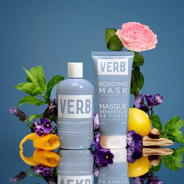 Verb Bonding Shampoo and Bonding Mask displayed with citrus, mint, flowers, and wood accents