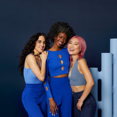 Three smiling models with dark, curly, and pink hair standing beside Verb Bonding Collection products
