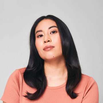 Model with long dark hair wearing a coral shirt in a Verb Forming Fiber styling campaign