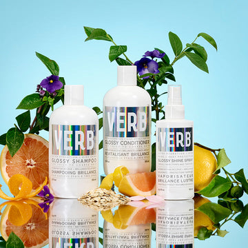 Verb Glossy Shampoo, Glossy Conditioner, and Glossy Shine Spray displayed with citrus fruits, flowers, oats, and reflective surfaces