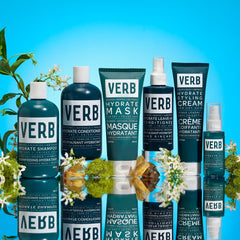 Verb Hydrate collection displayed with shampoo, conditioner, mask, leave-in conditioner, styling cream, and oil among flowers and reflective stones