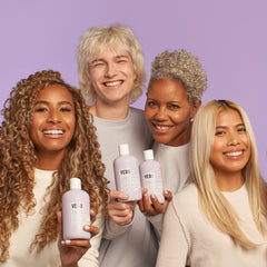 Four smiling models with different hairstyles and hair colors holding Verb Purple Shampoo bottles