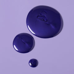 Glossy dark violet Verb Purple Shampoo texture shown in drops on a lavender background
